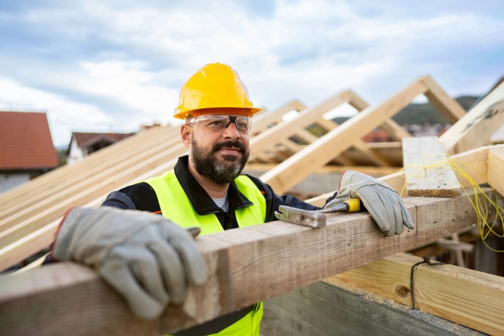Caucasian male roofer, working on a roof beam on a construction site